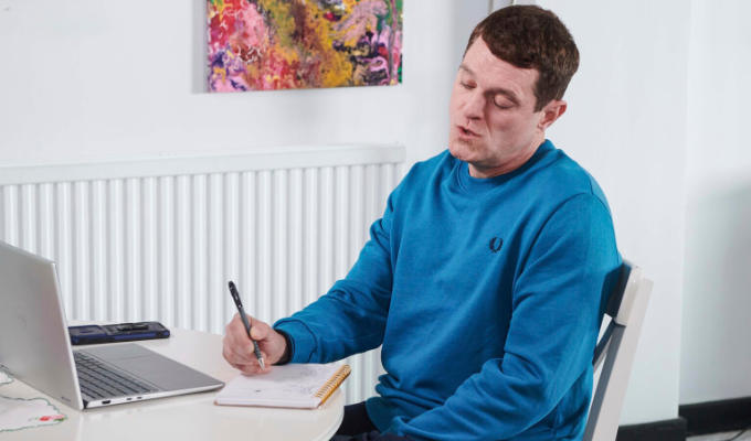 Gavin sitting at a desk writing